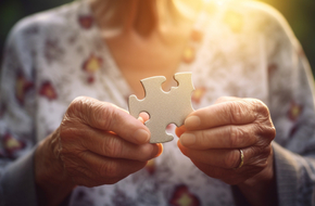 Starsza kobieta po przyjęciu leku na Alzheimera trzyma w ręku puzzla