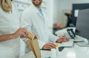 Farmaceuci w aptece pakują witaminy i minerały do suplementacji w neurologii