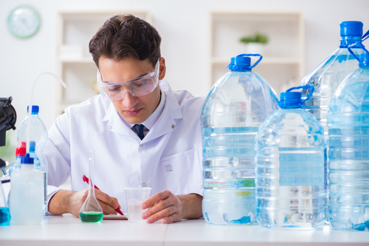 Zdjęcie przedstawia naukowca w laboratorium, analizującego próbki wody w kontekście badań nad mikroplastikiem w ludzkim mózgu.