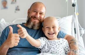 Mężczyzna z dzieckiem w szpitalnym łóżku, w trakcie leczenia onkolicznego